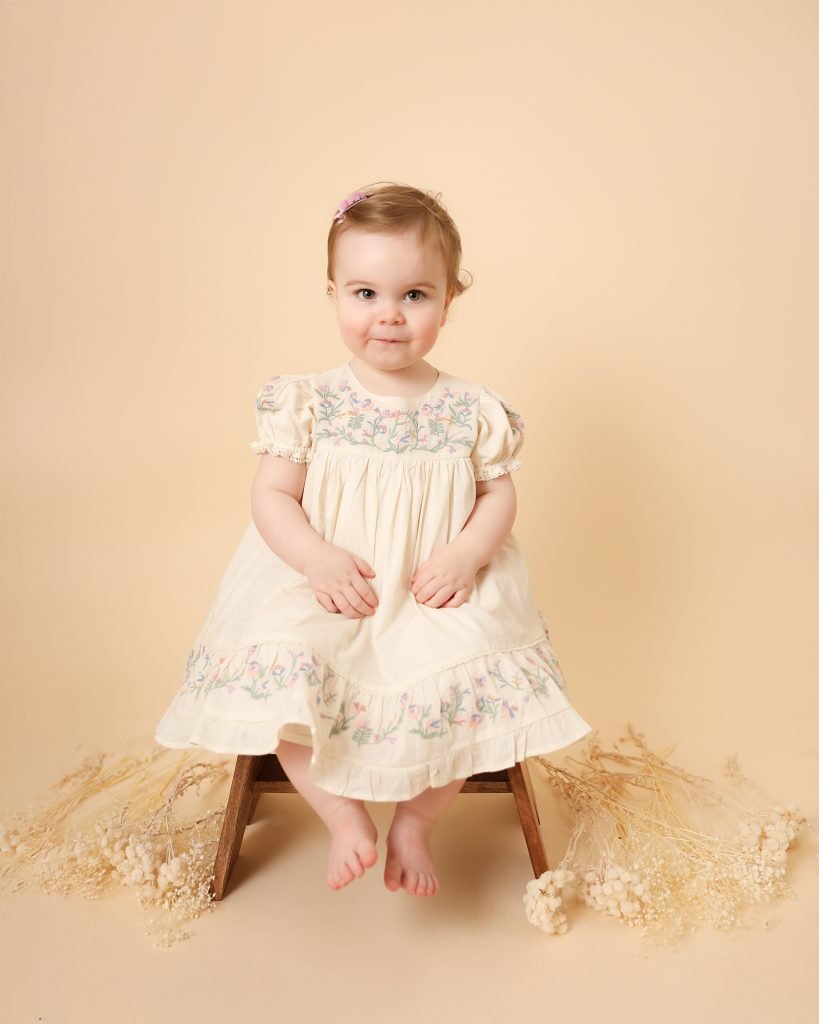 Classic portrait of a young girl in boho style with a soft cream background.