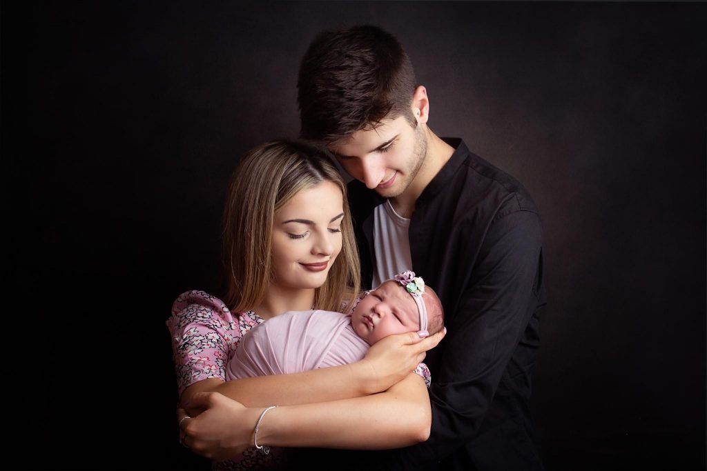 New parents lovingly holding their newborn baby, adjusting to the first few weeks of parenthood