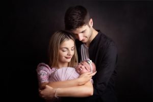 New parents lovingly holding their newborn baby, adjusting to the first few weeks of parenthood
