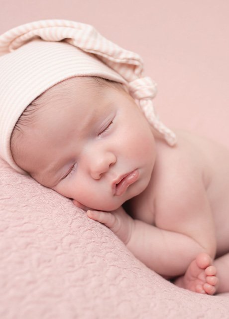 Newborn baby girl in a soft pink sleep hat, peacefully resting – Daisy May Photography, newborn photographer in Co. Armagh, Northern Ireland.