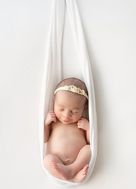 Newborn baby girl gently cradled in a white sling – Daisy May Photography, newborn photographer in Co. Armagh, Northern Ireland.