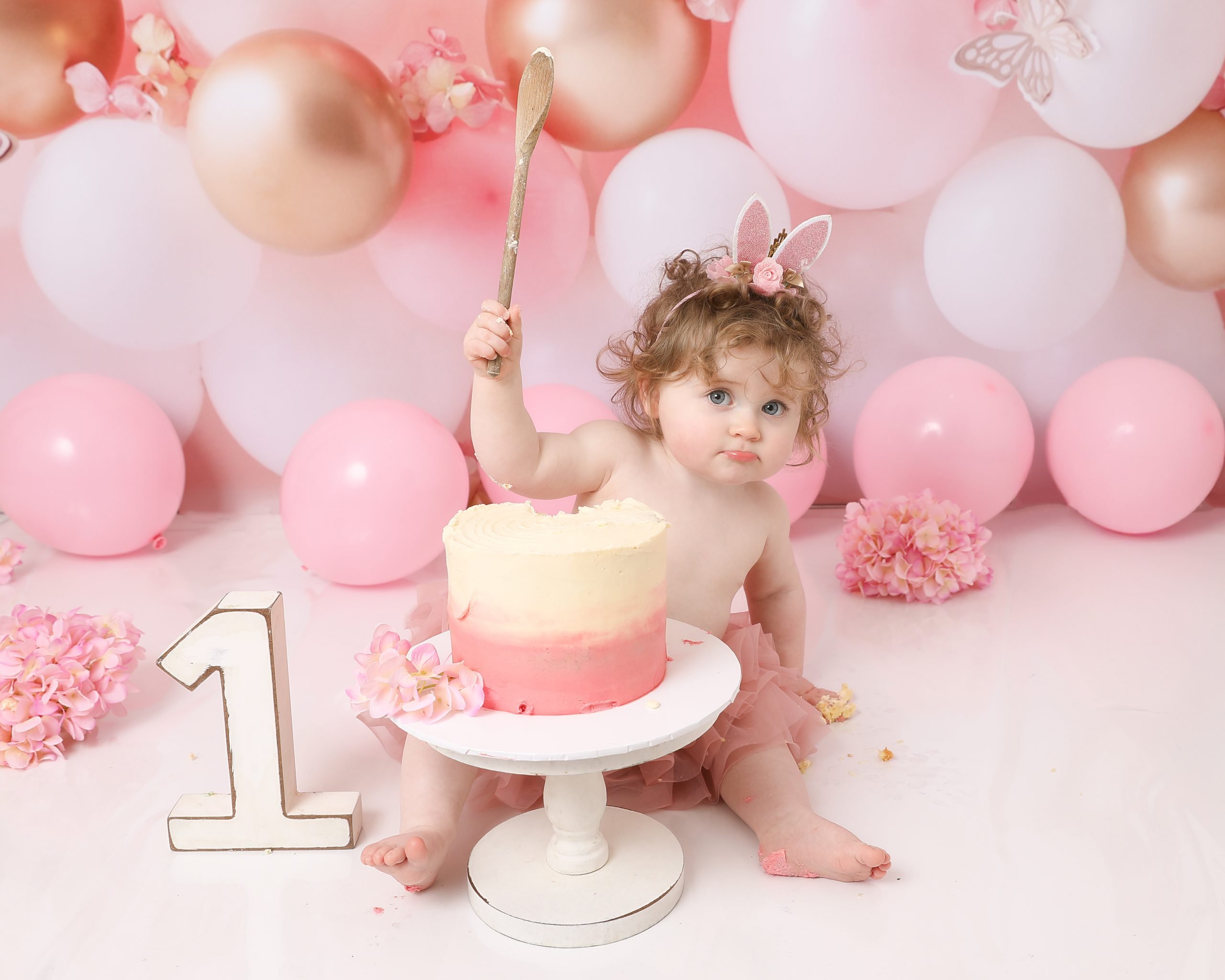 Girl enjoying her 1st birthday cake smash session at Daisy May Photography in County Armagh.